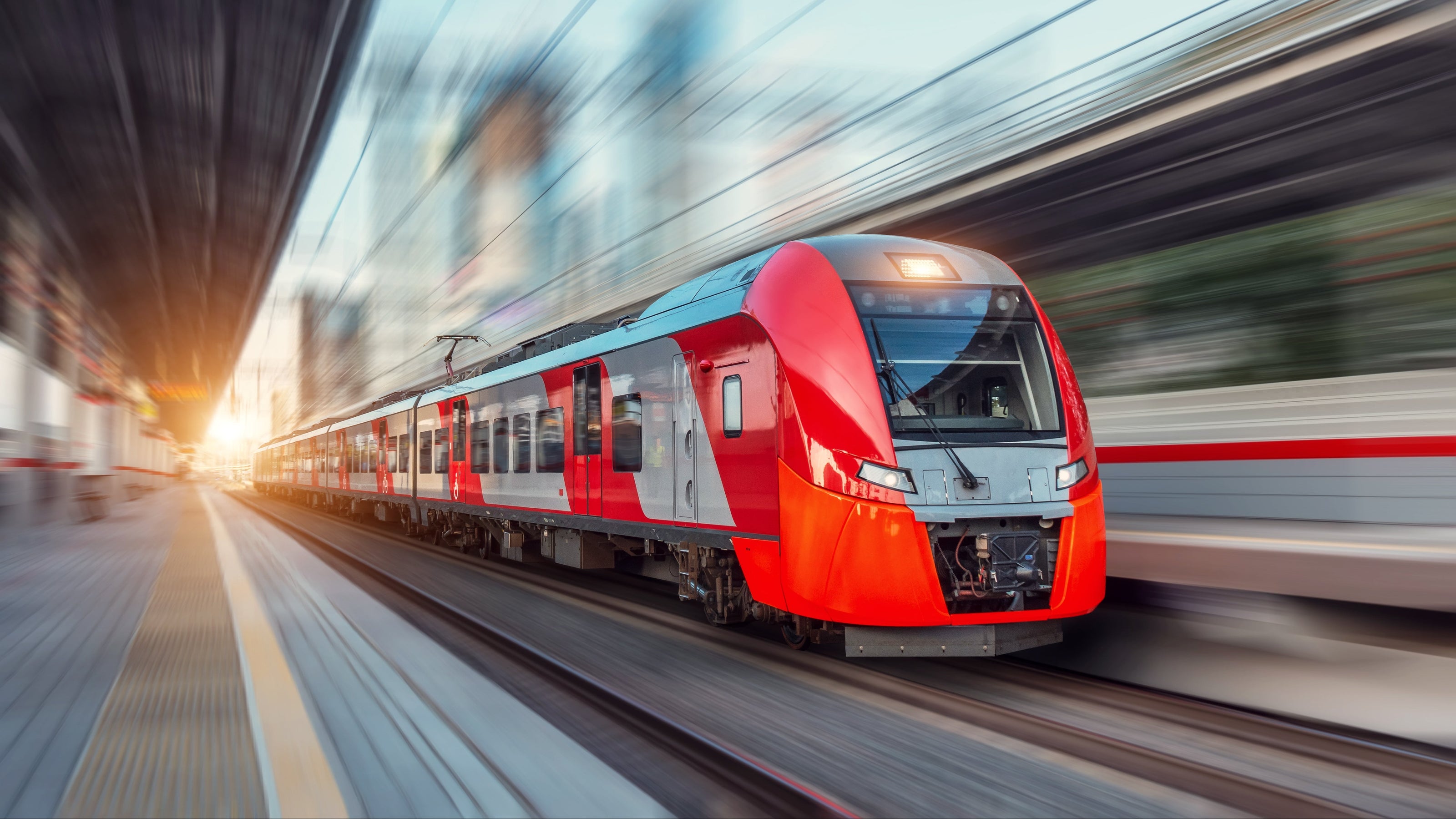 Red and gray train speeding along tracks with a blurred background